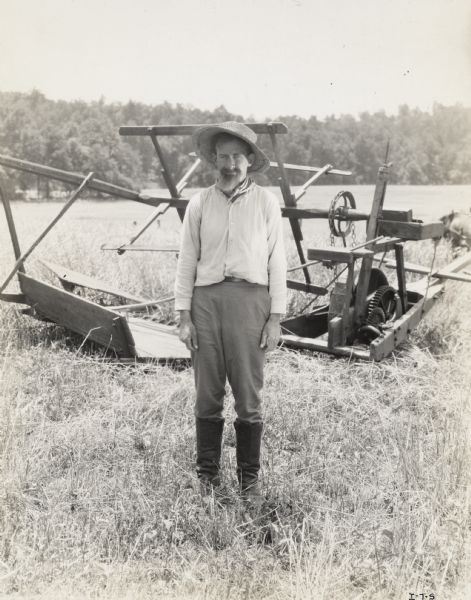 A production still for the Fox Hearst film "Romance of the Reaper". The film was produced by International Harvester at Walnut Grove to celebrate the Reaper Centennial. A man dressed as a farmer is standing in front of a replica of McCormick's first reaper. The man may have been a local resident recruited for the film.