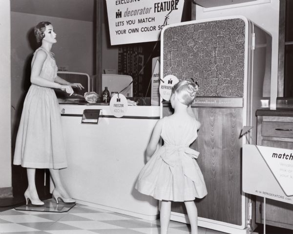 Two female mannequins are standing with an International Harvester freezer and refrigerator. This display may have been at the International Harvester headquarters in Chicago, Illinois.