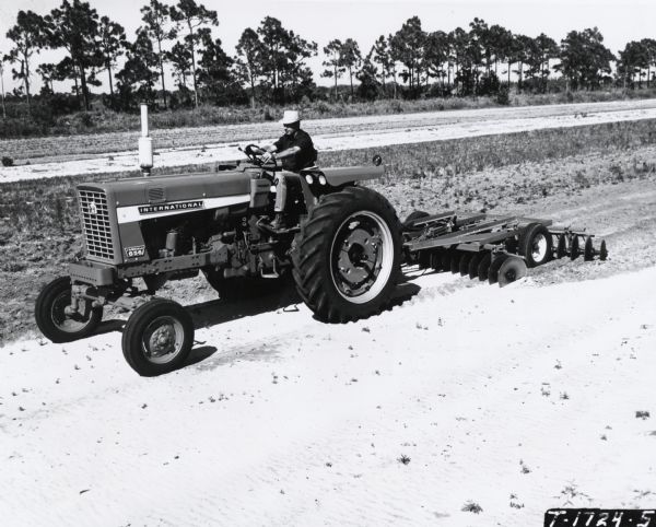 Slightly elevated view of a man operating a 656 Hydrostatic Tractor with a speed-ratio control lever. According to a press release caption: "The tractor can be adjusted to any desired forward speed between zero and twenty miles per hour to exactly match speed and drawbar pull to engine capacity."