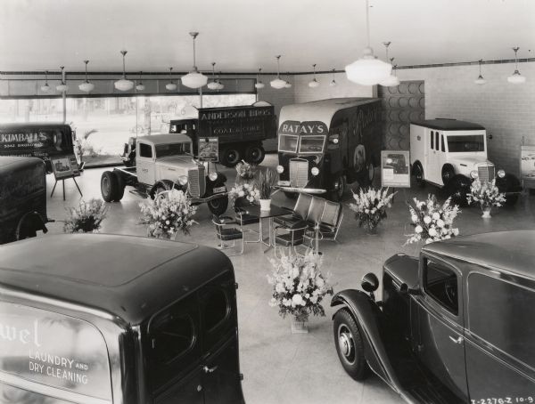 A dealership showroom with International trucks on display. Original caption reads: "Company sales room and service station 2665 N. Elston Ave; Chicago, Illinois. Public opening Thursday evening September 24th. Taken by Kaufman and Gabry(?) with W.T. Schuathomt(?).
