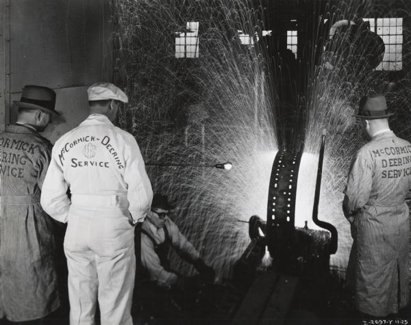 Branch service managers watch welding at Tractor Works. Original caption reads: "Tractor Works, Branch service managers watching welding of wheels. Taken by McQuinn".