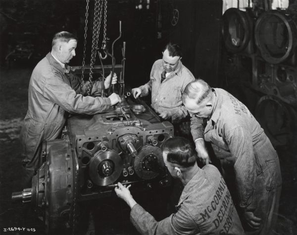 Branch service managers inspect TracTracTor (crawler tractor) assembly at Tractor Works (factory). Original caption reads: "Tractor Works, Branch service managers inspecting at one stage of assembly of Trac-Tractors. Taken by McQuinn".