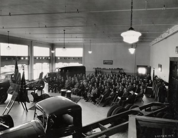 Elevated view of a group of International truck dealers gathered for a meeting. Caption on photograph reads: "Dealer meeting at Motor Truck Branch."
