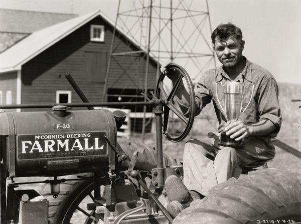 Plowing champion Carl Shoger holding a trophy on his Farmall F-20 tractor. Original caption reads: "Carl Shoger and his F-20 and Little Genius Plow and 1935 Cup Wheatland Plowing Match (Illinois) taken by B.B.H."
