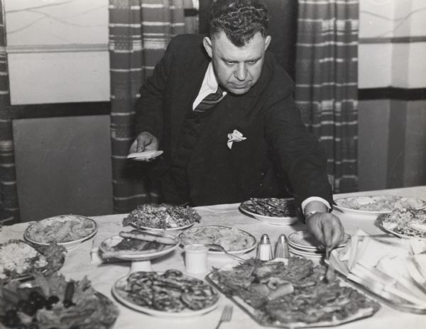 International Harvester employee M. Steele reachING over a table of hor d'oeuvres at an International truck sales meeting.