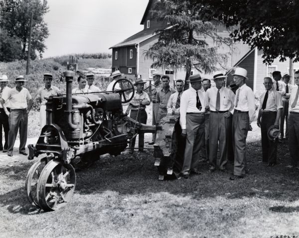 People gathered around a Farmall Regular tractor on the farm of Clarence L. Dauberman. Original caption reads: "Sydney G. McAllister, chairman, executive committee, the International Harvester Company, July 31, 1941, was one of the speakers on the NBC National Farm and Home Hour which was broadcast from the Clarence L. Dauberman farm near Kaneville, Illinois. In July, 1934, Mr. Dauberman changed the cylinders of his Farmall for high compression and the broadcast ceremonies over WLS were to honor Mr. Dauberman for being the first farmer to adopt the high compression tractor in the United States. A bronze plaque (see photograph I-2511-EE) was presented to Mr. Dauberman for his part in developing the high-compression tractor."