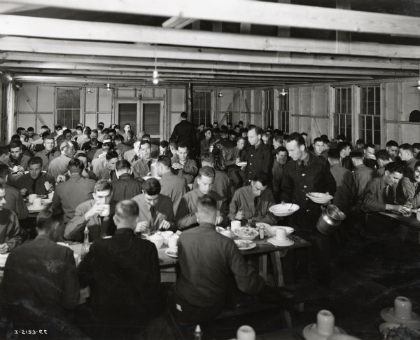 Men eat a meal in a mess hall at Fort Sill. Draftee Charles J. Richard is among the men. Richard was a former International Harvester employee of Oklahoma City. A complete story was published in the August, 1941 edition of <i>Harvester Works</i>.
