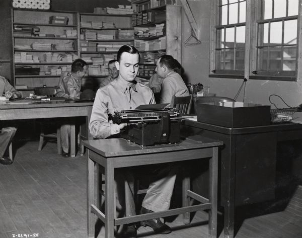 Private Roger Kolkmeyer types on a typewriter. Kolkmeyer was a company clerk at Fort Sill. He was a former employee of the (?) Department general office of International Harvester.