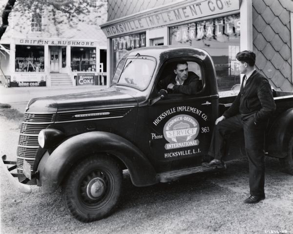 Salesman Walter E. Seliguan at the wheel of an International truck, talking with J.G. Lauchner, general manager of the Hicksville Implement Company. The Hicksville implement company was an International Harvester dealership.