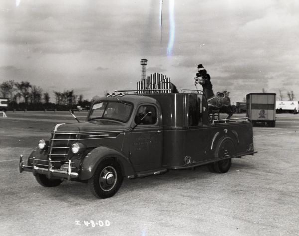 Two men an International D-15 truck equipped with a calliope and carousel horses. The truck was owned by Consumers' Advertising Company of Chicago.