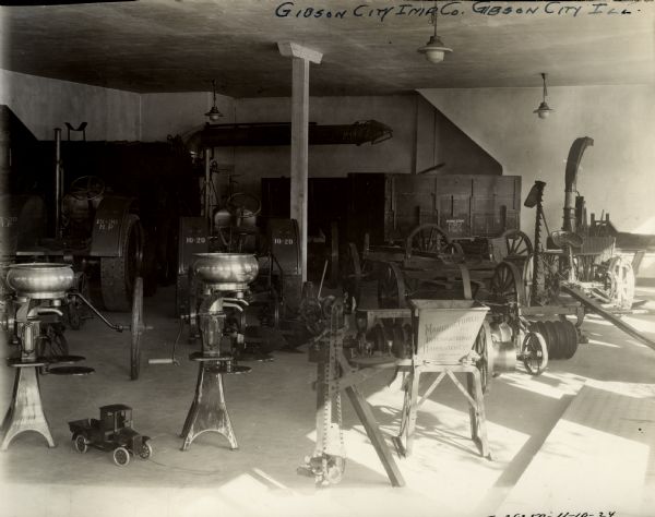 Showroom of Gibson City Implement Company, an International Harvester farm equipment dealership. Equipment on display includes a 10-20 tractor, a 15-30 tractor, cream separators, a feed grinder, a Weber wagon, a sickle-bar mower and a toy truck.