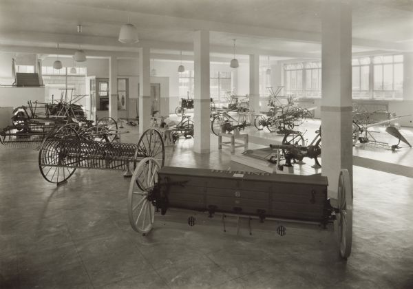 Farm equipment on display in the showroom of International Harvester's Nuess branch house in Germany. A Deering grain drill is prominent in the foreground.