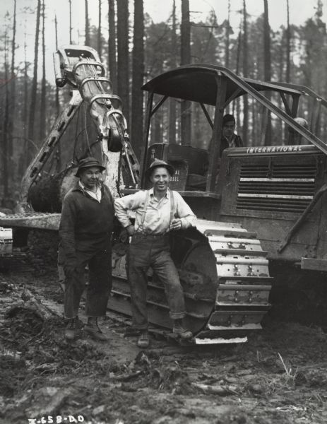 Three Men with an International TD-18 TracTracTor (crawler tractor) in forest. The tractor was owned by Wells and Allen, and was equipped with a Carco winch.