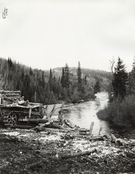 International TD-35 Diesel TracTracTor (crawler tractor) owned by A.C. Duval.  A man uses the machine to push logs into the Spanish River. The river is located west of Sudbury in Ontario, Canada.