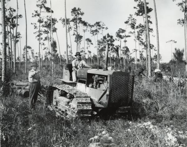 Men with an International TD-35 TracTracTor (crawler tractor) engaged in logging operations. According to the original caption, the tractor "logs an average of 8 to 9 thousand board feet of lumber a week for C.R. Lee.  The tractor can easily pull 25 logs averaging 35 feet in length. In a ten hour day the tractor makes twenty-five to thirty trips of from 200 yards to one-quarter mile (one way). Only a gallon of 8-cent Diesel fuel is used per hour. This tractor does the work of two smaller size sidtillate tractors formerly used, each of which used 1.5 gallons of fuel an hour."