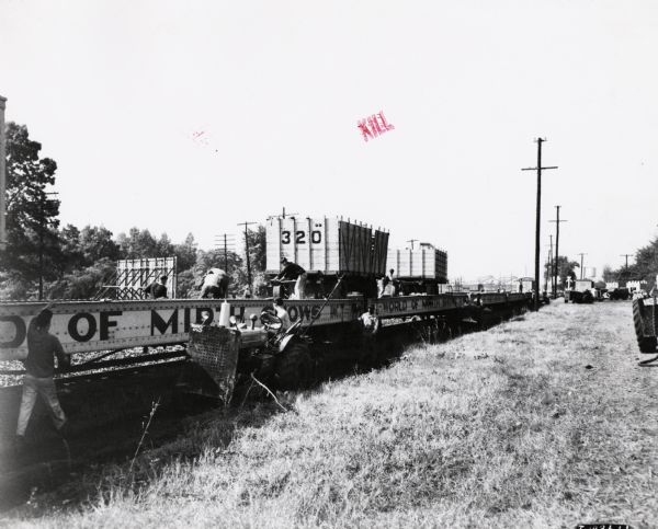 Men unload rail cars for the "World of Mirth Shows," an American traveling carnival with rides and a sideshow. International ID-6 diesel wheel tractors assist in the unloading. 