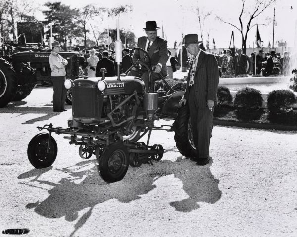 Two Minnesota dealers, Glidden Toldt and Myron Syverson of Ornsby, inspect a Farmall Cub Tractor. The men were likely attending an International Harvester event celebrating 100 years in Chicago.