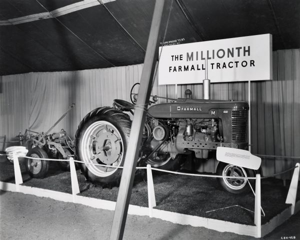 The one millionth Farmall tractor on display, likely at International Harvester's "100 Years in Chicago" celebration. A sign reads: "The Millionth FARMALL Tractor built recently at Farmall Works, Rock Island, Illinois. It is a FARMALL M, the largest of the FARMALL family, destined to work on a large farm. Of the million FARMALL tractors delivered to American farms, over a period of 24 years, nearly all are still on the job."