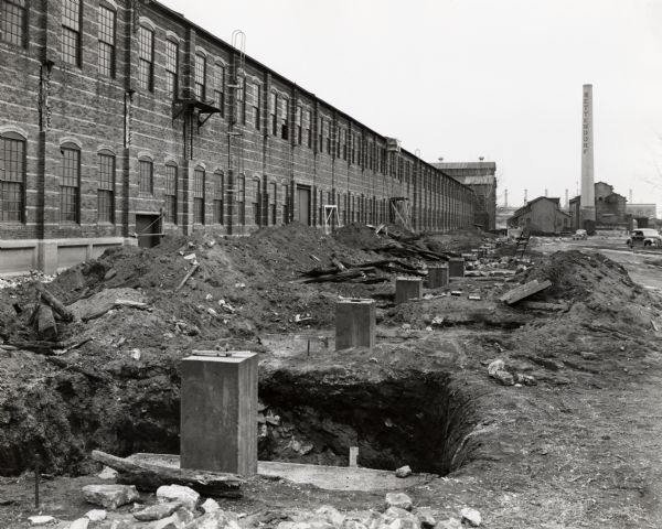 Construction site, probably at International Harvester's Bettendorf Tank Arsenal (factory). A large hole is in the foreground.