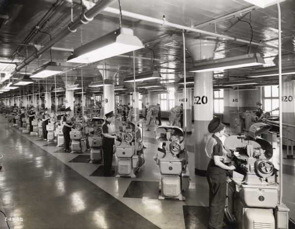 Female factory workers operating automatic screw machines at an International Harvester aircraft torpedo factory. Caption on photograph reads: "Two batteries of automatic screw machines all operated by women employees."