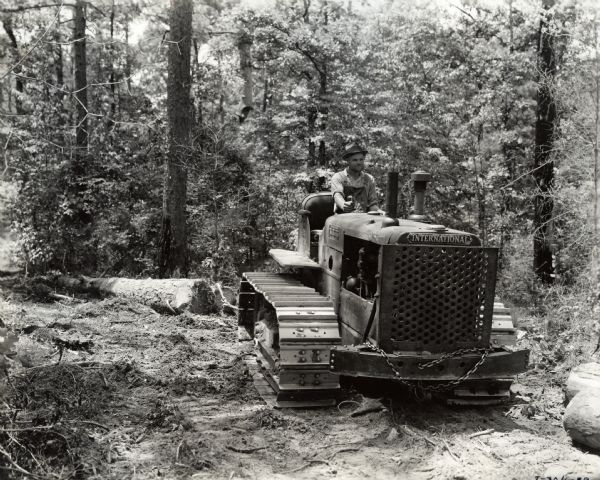 Man operating a crawler tractor in old growth forest. Origional caption reads: "International TD-35 Diesel TracTracTor owned by M.C. Hamilton, Fulton, Alabama, skidding logs in big virgin timber owned by the Scotch Lumber company."