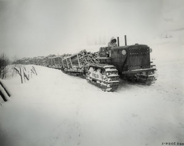 Man pulling logs through the snow with a TD-18 TracTracTor (crawler tractor). Original caption reads: "TD-18 Demonstration pulling total load of 163 tons of logs."