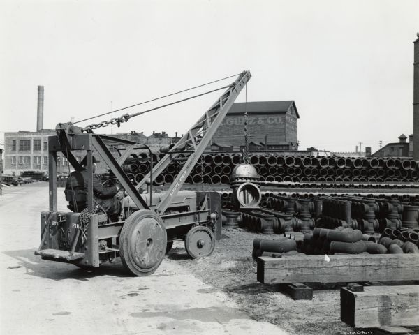 International I-4 industrial tractor with crane owned by the Milwaukee Waterworks. Original caption reads: "The city of Milwaukee, Wisconsin, purchased this I-4 and Mercer crane for its Waterworks Department. This unit is one of two. The equipment is used to move material in the municipal service building, and for loading and unloading freight cars and trucks. The equipment has operated 2-4 hours for a total of 1500 hours. It uses one gallon of gasoline per hour at 14 cents per gallon.  Lubrication costs on average two cents per hour."