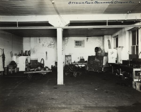 Interior, most likely a shop or service area, at the Ottawa Farm Machinery Company, an International Harvester dealership. In the shop are stools, carts, chains, wires, canisters, and workbenches.