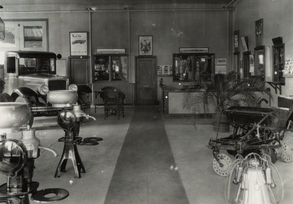 Showroom of the Muncie International Company, an International Harvester dealership. The showroom includes a truck, furniture, a desk area, and farm equipment. Posters and photographs are above the doors and windows.