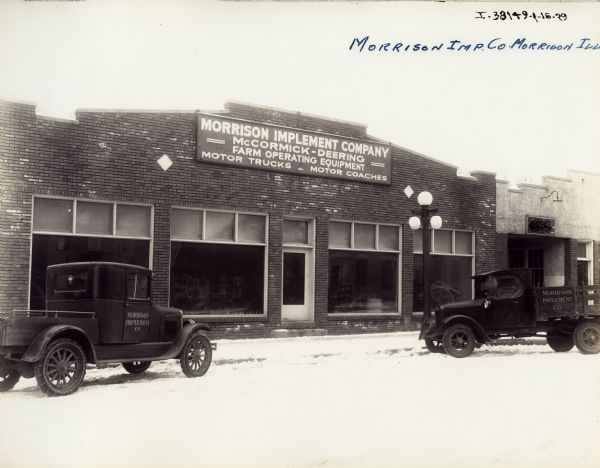 Exterior of the Morrison Implement Company, an Inernational Harvester dealership. Two trucks are parked outside the storefront which has large show windows. Snow is on the ground.The sign above the entrance reads: "Morrison Implement Company; McCormick-Deering Farm Operating Equipment; Motor Trucks-Motor Coaches."