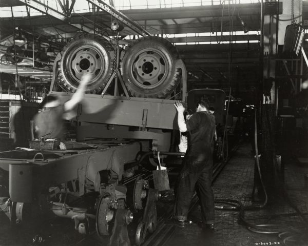 Factory workers on the assembly line (possibly at International Harvester's Ft. Wayne Works) with M-5-6 trucks. Original caption reads: "The trucks are the military model No. M-5-6, originally sold to the United States Army. These trucks have been diverted under the Lease-Lend Program to Russia."