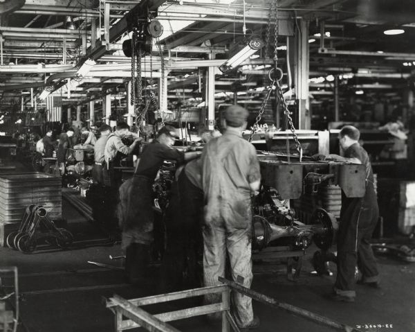 Factory workers on an assembly line with M-5-6 trucks, possibly at International Harvester's Ft. Wayne Works. Original caption reads: "The trucks are the military model No. M-5-6, originally sold to the United States Army.  These trucks have been diverted under the Lease-Lend Program to Russia."