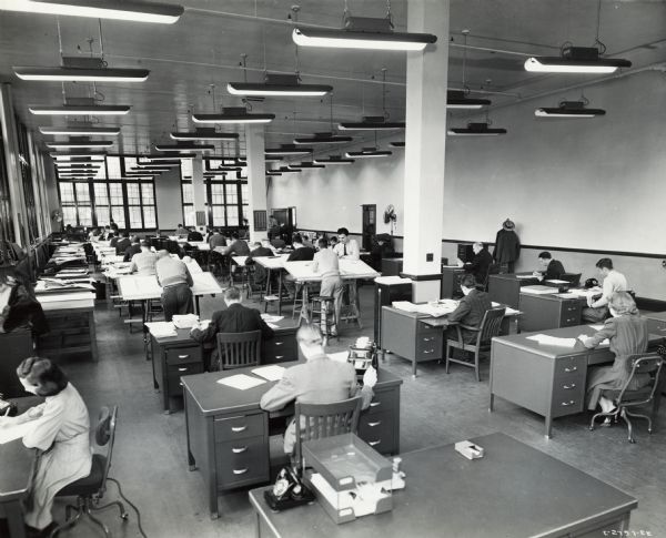 Men and women at drafting tables at International Harvester's St. Paul Works. Original caption reads: "Medium Caliber Artillery Gun Manufacture. The engineering department of the new (St. Paul) Works where all of the preliminary designing and blueprint work in connection with the manufacture of the new gun has been done."