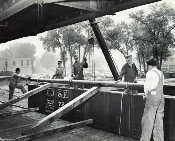 Factory workers unloading a rail car on a loading dock at International Harvester's St. Paul Works. Original caption reads: "Medium Caliber Artillery Gun Manufacture. Materials for the new Works being unloaded at the plant."