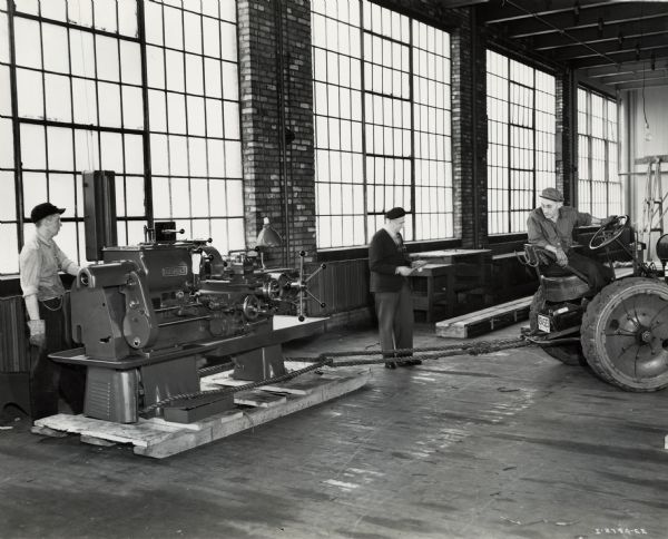 Workers use an industrial tractor to move factory machinery into place at International Harvester's St. Paul Works. Original caption reads: "Medium Caliber Artillery Gun Manufacture. A machine being placed in the building preparatory to the beginning of the manufacture."