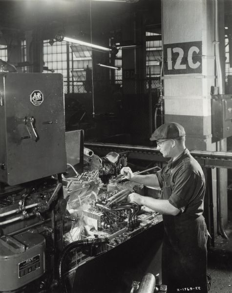 Factory worker producing artillery shells at International Harvester's Milwaukee Works. Original caption reads: "75-Millimeter Shell Manufacture. In this operation the shells are given the final turning on a Fay automatic lathe to establish the outside diameter. Finished tolerances of .0035 are required on this operation."