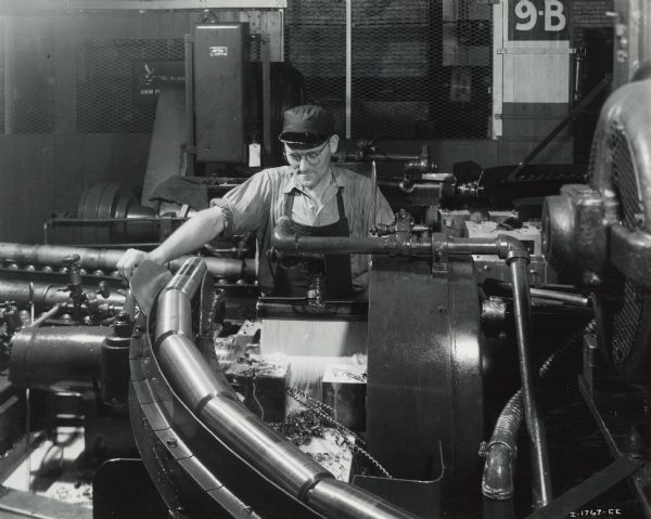Factory workers producing artillery shells at International Harvester's Milwaukee Works. Original caption reads: "75-Millimeter Shell Manufacture. In this operation the shell receives the first rough turning to machine the exterior. The operation is performed on a Gisholt Simplimatic automatic lathe. The outside and the base of the shell are given a rough finish in a single operation."