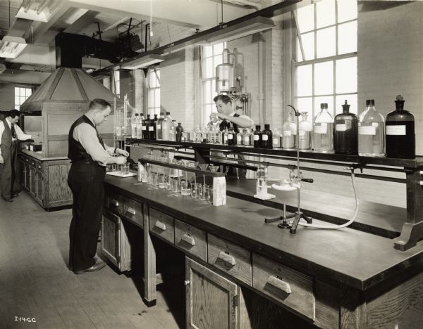 Men working in a laboratory at an International Harvester factory producing aircraft torpedoes. Original caption reads: "All materials used in the torpedo must be of the finest and meet exacting specifications. A complete modern physical and chemical laboratory is operated in connection with the plant  to test materials. This is a section of the torpedo plant chemical laboratory."