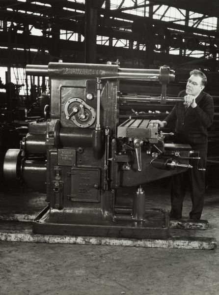 Original caption reads: "Walter R. Hallberg, superintendent of Harvester's special machine tool shop, inspects a rebuilt milling machine placed in operating condition." The shop repaired and rebuilt machines used in International Harvester factories.
