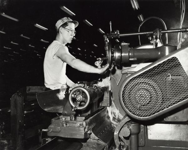 Factory worker helps produce guns at International Harvester's St. Paul Works.  Original caption reads: "One of the lathes used in gun production operated by Arthur Fitch."