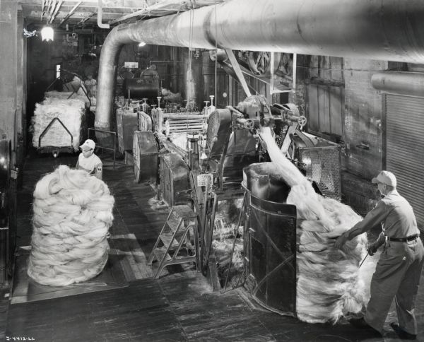 Factory workers process sisal fiber to produce binder twine, possibly at the McCormick Twine Mill. Original caption reads: "The raw material for twine enters this machine as fiber, comes out in a blend called 'sliver.' It has been properly treated with an emulsion lubricant, and insect and rodent repellent. Weight-checking is constant to assure uniformity of finished product."