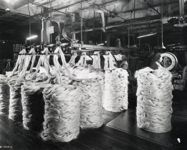 Female factory workers inspect sisal fiber, possibly at the McCormick Twine Mill. The fibers were stacked in piles and then weighed on a floor scale.