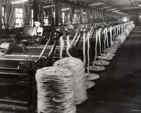 Female factory workers spinning sisal, possibly at the McCormick Twine Mill. Original caption reads: "In the spinning department, this battery of "jennies" turn the prepared sliver into finished binder or baler twine. These machines are where IH twine gets its scientific drawing and 'twist'-not so tight as to kink, nor so loose as to ravel-but just right to become a firm, smooth, uniform product."