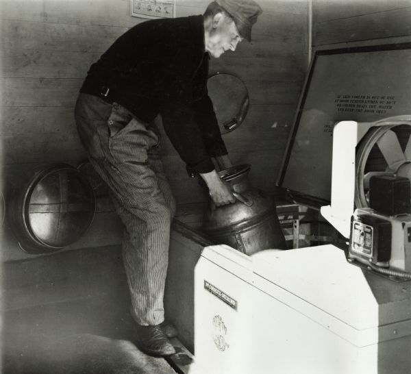 Fred Esser puting a milk can into an McCormick-Deering 6 can milk cooler.