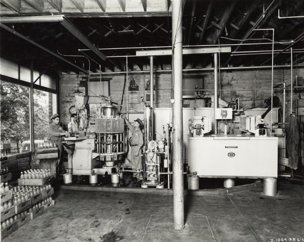 Workers packaging bottles of soda into crates, some of which are labeled "Orange Crush." A McCormick-Deering cooler is standing nearby. Original caption states: "1128-30 East Fourth St. Owner Ray V. Kamp. Mc D-(2) compressor water cooler."