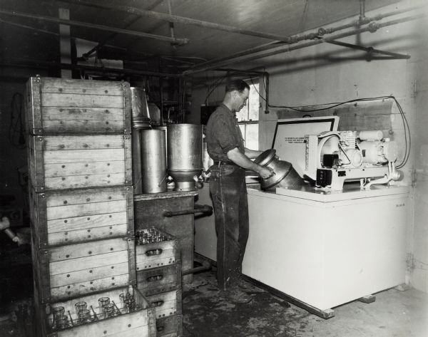 Richard Brackett, President of the Wisconsin Dairyman's Association, stands with a milk can near a McCormick-Deering cooler. Original  caption states: "Pres. Wisconsin Dairymen's Association, and his 10 can McCormick-Deering milk cooler."