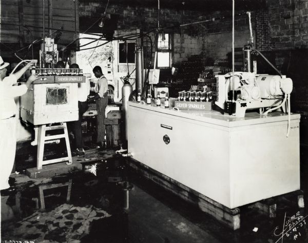 Workers packing bottles (possibly of soda) near a McCormick-Deering  ten-can cooler at Parmlee Bottling Works.