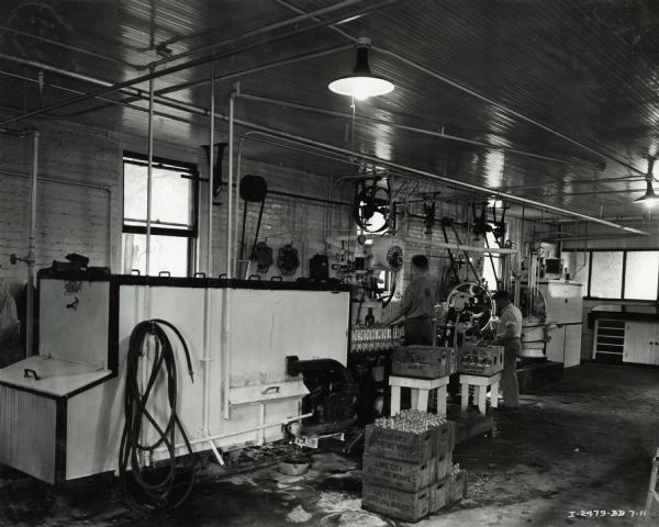 Workers packing bottles (possibly of soda) near a McCormick-Deering 8 can cooler at Lake City Bottling Company.