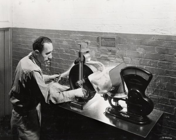 Factory worker tests binder twine, possibly at the McCormick Twine Mill. Original caption reads: "Length of twine is accurately predetermined by what the company calls the 'sliver test.' Here a given quantity of the correct blend of fibers is carefully weighted before spinning to certify that the spun product will meet length, strength and weight specifications."