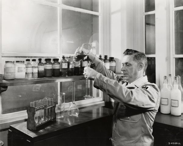 A lab technician tests binder twine, possibly at the McCormick Twine Mill. Original caption reads: "Resistance to rot, insect and rodent damage, is established by careful analysis-according to standards developed by IH technicians. Effectiveness of the treatments is made known by exposing the twine, under extreme conditions, to destructive molds-and to field mice, rats, crickets, and other enemies of twine life. Laboratory technician is shown making an analysis of special twine oil."